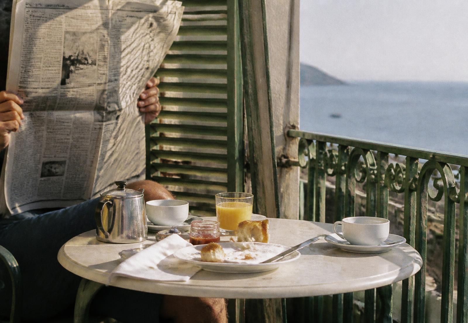 A guest behind a newspaper at late breakfast