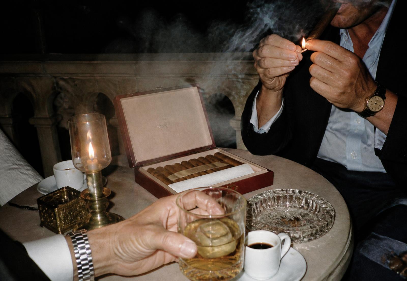 A cigar being lit after dinner beside a glass of Alexander