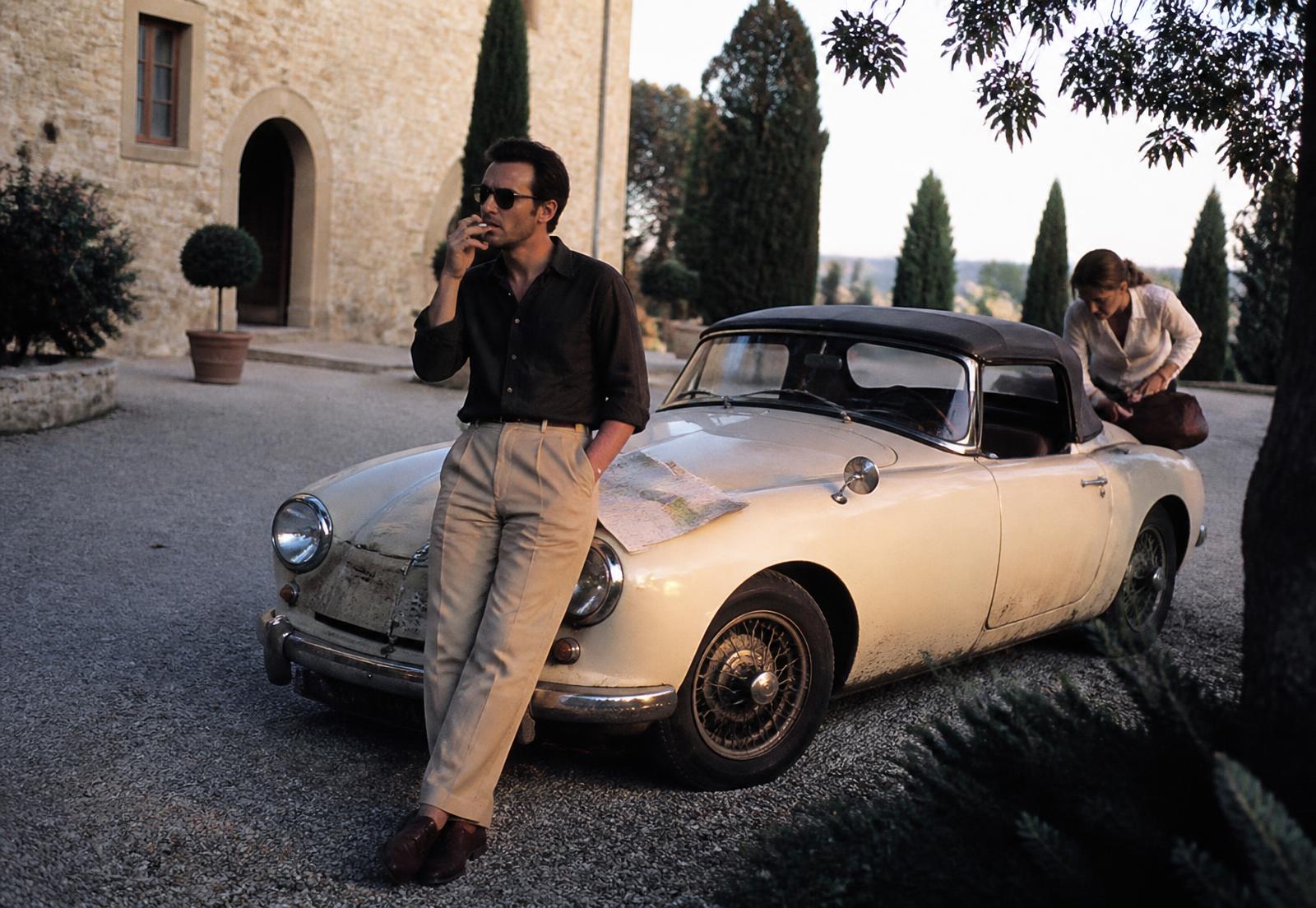 A guest waiting beside a vintage car before a journey inland